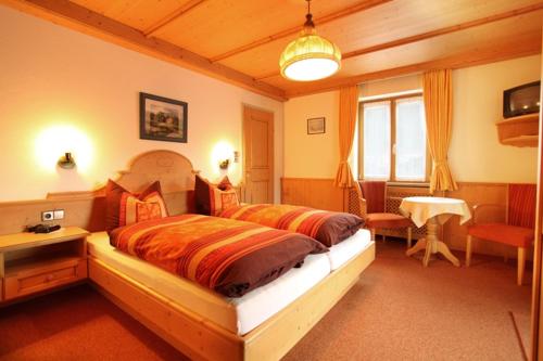ein Schlafzimmer mit einem großen Bett in einem Zimmer mit einem Tisch in der Unterkunft Beim Rottmeister in Reit im Winkl
