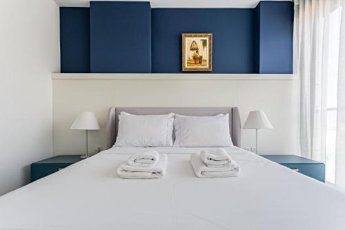 une chambre avec un grand lit blanc avec des serviettes dessus dans l'établissement WI-FI 300MB | Rooftop com Piscina em Jurerê #JA15, à Florianópolis