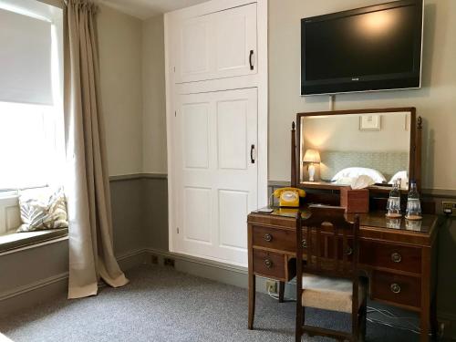 a bedroom with a mirror and a dresser and a tv at The Bridge House in Bridport
