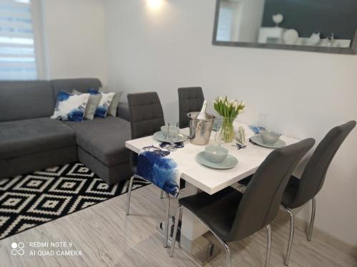 - un salon avec une table, des chaises et un canapé dans l'établissement Aqua Blue Apartament, à Reda