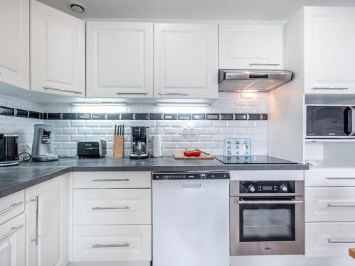 a white kitchen with white cabinets and appliances at Apartment Les Alizés-1 by Interhome in Carnac-Plage