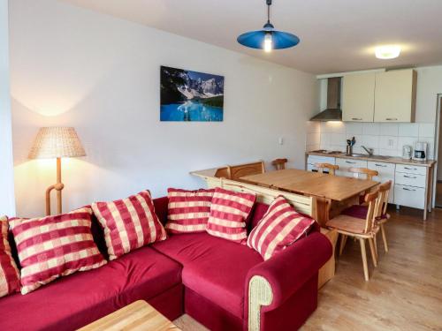 a living room with a red couch and a kitchen at Apartment Spatzennest - Top 7 by Interhome in Grünau im Almtal