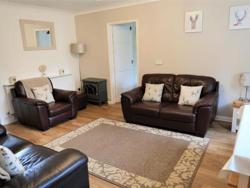 a living room with two leather couches and a rug at Holiday Home Woodhouse-6 by Interhome in Shermanbury