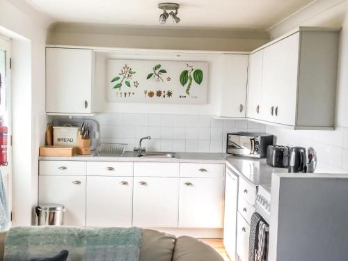 kuchnia z białymi szafkami i kanapą w obiekcie Holiday Home Woodhouse-5 by Interhome w mieście Shermanbury