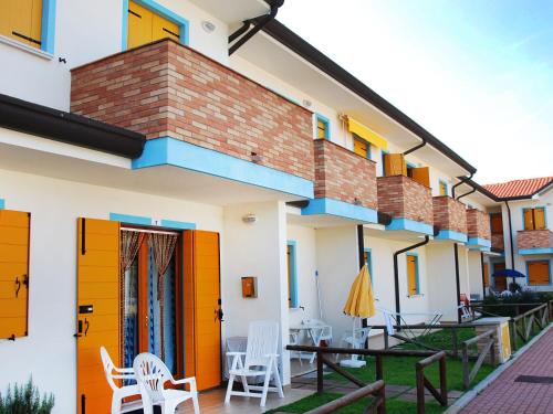 ein Haus mit orangefarbenen Türen und Stühlen auf einer Terrasse in der Unterkunft Apartment Solmare-38 by Interhome in Rosapineta