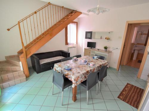 ein Wohnzimmer mit einem Tisch, Stühlen und einer Treppe in der Unterkunft Apartment Solmare-41 by Interhome in Rosapineta