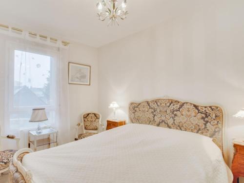 1 dormitorio con cama blanca y lámpara de araña en Apartment Le Hoche by Interhome, en Dinard