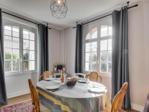 une salle à manger avec une table, des chaises et des fenêtres dans l'établissement Holiday Home Le Petit Biyou by Interhome, à Dinard