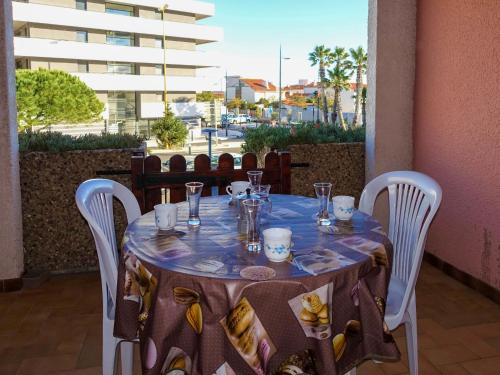 une table avec un chiffon bleu et des chaises blanches dans l'établissement Apartment Le Méditerranée-2 by Interhome, au Barcarès
