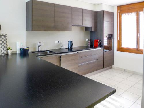 una cucina con piano di lavoro nero e armadietti in legno di Villa Casa Bellevue by Interhome a Grandvaux