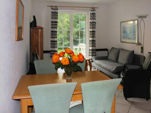 a living room with a table with a vase of orange flowers at Apartment Gollwitzer Park - Insel Poel-9 by Interhome in Gollwitz