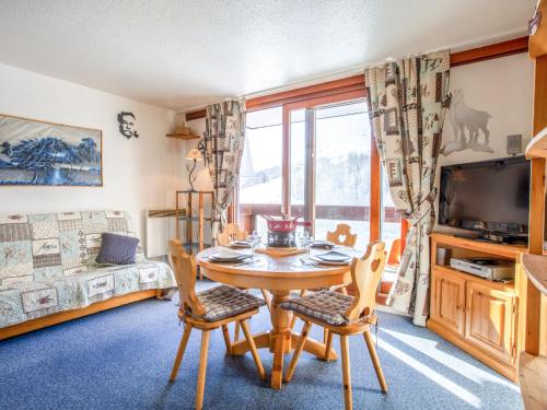 - un salon avec une table, des chaises et une télévision dans l'établissement Apartment Vostok Zodiaque-86 by Interhome, au Corbier