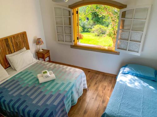 a bedroom with two beds and a window at Pousada Pe da Serra in Tiradentes