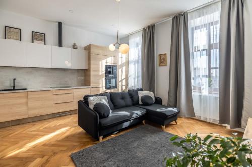 a living room with a black couch and a kitchen at Apartmány Marienhof in Znojmo