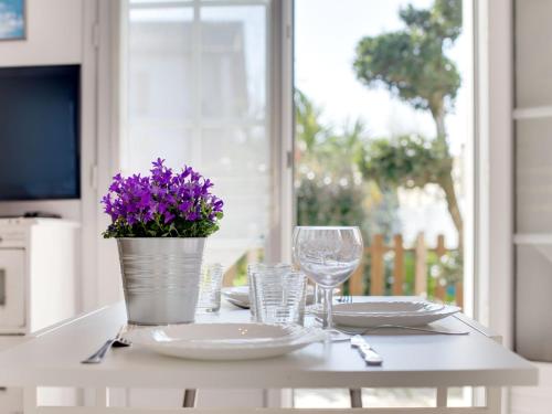 una mesa con platos y un jarrón con flores púrpuras en Studio Etxe Tikia, en Guéthary