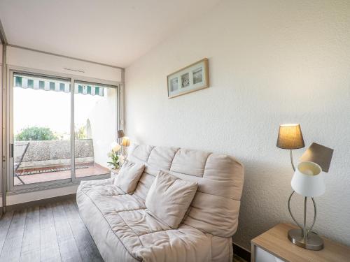 un salon avec un canapé blanc et une grande fenêtre dans l'établissement Apartment Le Quai aux Fleurs-5 by Interhome, au Grau-du-Roi