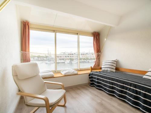 a bedroom with a bed and a chair and a window at Apartment Le Nirvana-2 by Interhome in Le Grau-du-Roi