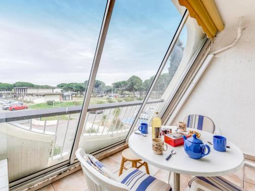 une table et des chaises dans une pièce avec une grande fenêtre dans l'établissement Studio Escale Plage-2 by Interhome, au Grau-du-Roi