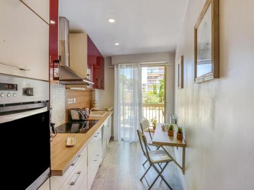 une cuisine avec des armoires blanches et une table avec des chaises dans l'établissement Apartment Le Poséidon by Interhome, à Cagnes-sur-Mer