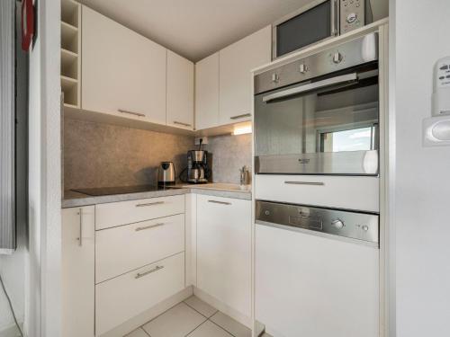 une cuisine avec des armoires blanches et des appareils en acier inoxydable dans l'établissement Apartment Camargue Village-4 by Interhome, au Grau-du-Roi