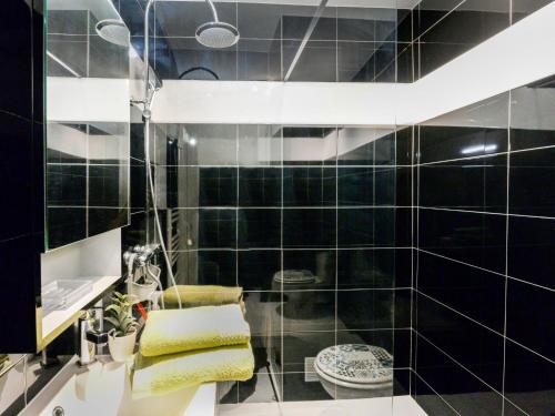 La salle de bains est pourvue de murs carrelés noirs et d'un lavabo. dans l'établissement Studio Le Baccara by Interhome, à Cagnes-sur-Mer