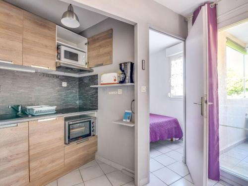 - une petite cuisine avec des placards en bois et un four micro-ondes dans l'établissement Apartment Les Rives du Lac-8 by Interhome, au Grau-du-Roi