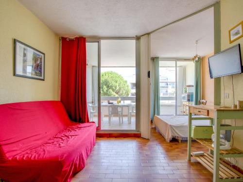 Schlafzimmer mit einem roten Bett und einer Glasschiebetür in der Unterkunft Apartment Floralies I-5 by Interhome in Le Grau-du-Roi