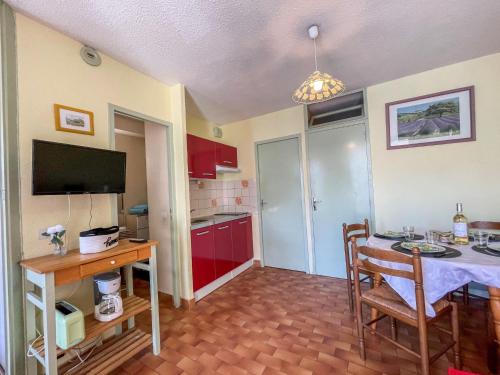 une chambre avec une table et une cuisine avec des placards rouges dans l'établissement Apartment Floralies I-5 by Interhome, au Grau-du-Roi