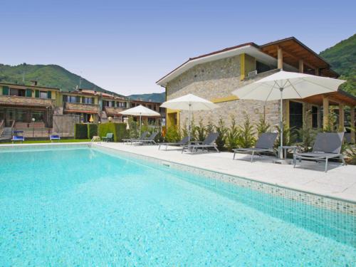 a swimming pool with chairs and umbrellas next to a building at Apartment Elettra-9 by Interhome in Crone