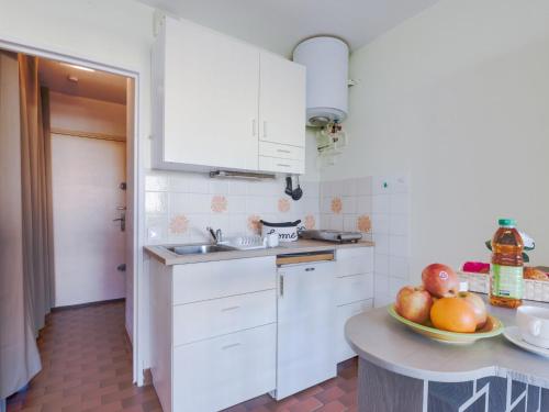 - une cuisine avec des placards blancs et un bol de fruits sur une table dans l'établissement Studio Floralies I-6 by Interhome, au Grau-du-Roi