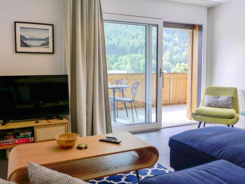 a living room with a couch and a television and a balcony at Apartment Lantau by Interhome in Kandersteg