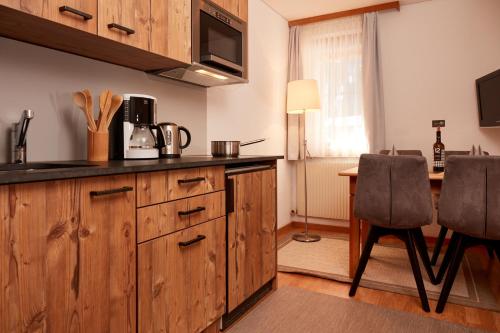 a kitchen with wooden cabinets and a table with chairs at Dà Ingo - Apartments & More in Damuls