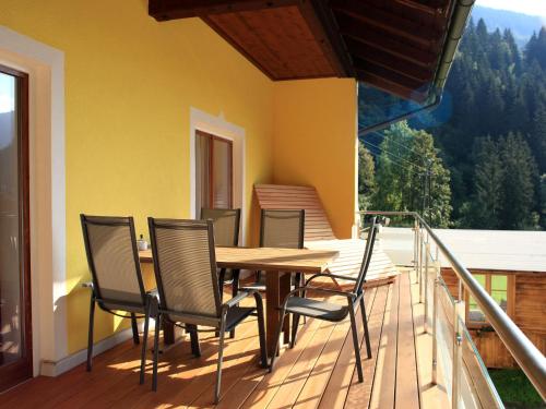 una terrazza in legno con tavolo e sedie sul balcone. di Apartment Schwarzwald by Interhome a Radenthein