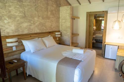 1 dormitorio con cama blanca y baño en Aquarela Praia Hotel, en Arraial d'Ajuda
