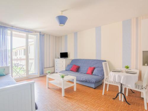 Una sala de estar con un sofá azul y una mesa. en Studio Le Saint François by Interhome, en Saint-Aygulf