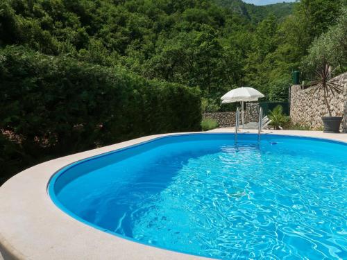 a blue swimming pool with an umbrella and an umbrella at Holiday Home Karin by Interhome in Lovran