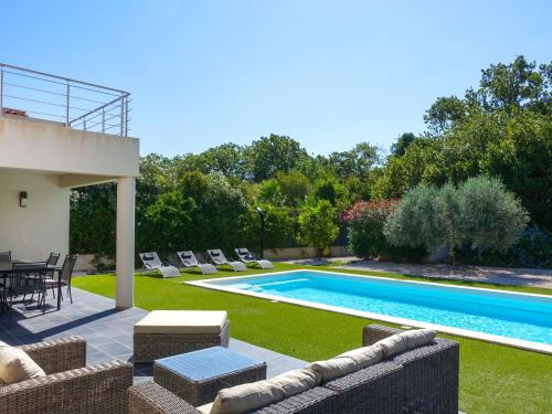 um quintal com uma piscina com cadeiras e uma mesa em Villa Bastide de la Mer by Interhome em Bormes-les-Mimosas