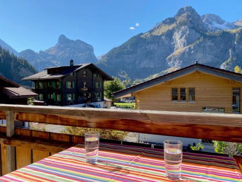 a table with two glasses on a balcony with mountains at Apartment Haus Lohnerblick by Interhome in Kandersteg