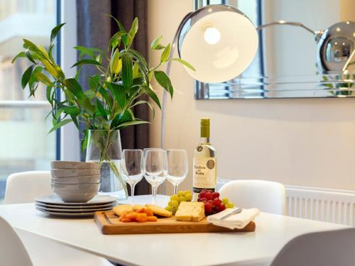 a table with a plate of food and wine glasses at Apartment Canary Gateway- Canary Wharf by Interhome in London