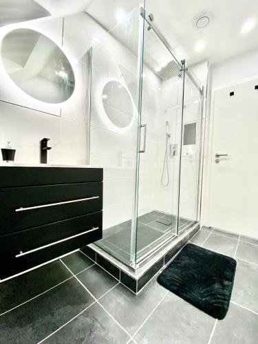 a bathroom with a glass shower and a black rug at Living Solution 24 Karlsruhe in Karlsruhe
