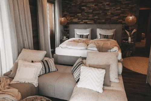 a bedroom with a bed and a couch with pillows at Jufenalm BOHO & Wellnesshotel in Maria Alm am Steinernen Meer
