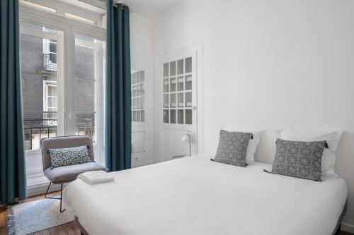 une chambre avec un lit blanc et une chaise dans l'établissement Chaleureux appartement proche de la Place Graslin, à Nantes