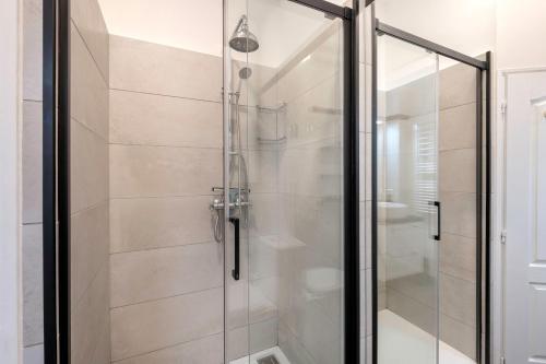 une douche avec une porte vitrée dans une salle de bain dans l'établissement Chaleureux appartement proche de la Place Graslin, à Nantes