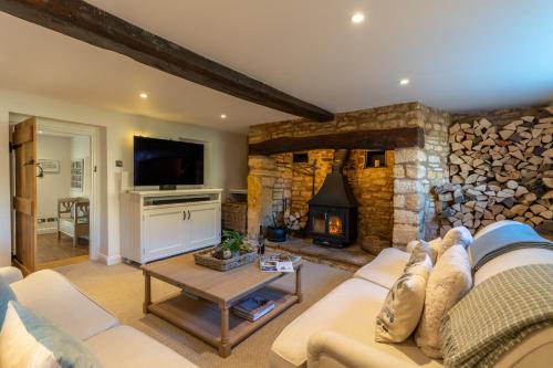 uma sala de estar com um sofá e uma lareira em Yew Tree Cottage em Longborough