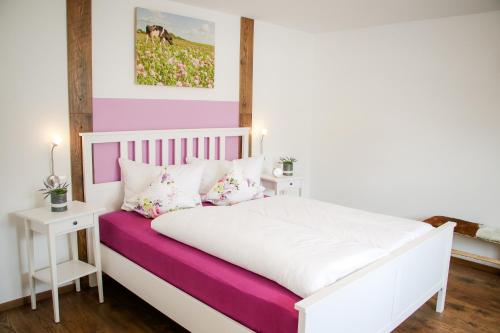 a bedroom with a white bed with pink and purple sheets at Ferienhaus Zum alten Kuhstall in Hayingen
