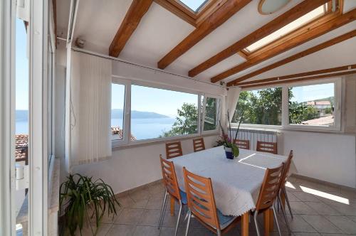 a dining room with a table and chairs and windows at Apartments & Rooms Nada in Brseč
