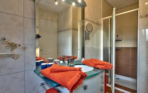 a bathroom with a sink and a shower with orange towels at Lanévry, Ville d'Ys in Kerlaz