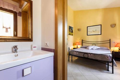 a bathroom with a bed and a sink and a mirror at Casa Marcella in Costa Rei
