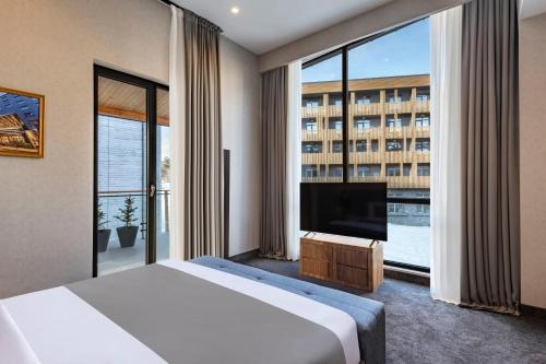 a hotel room with a bed and a large window at Bristol Hotel and Spa Bakuriani in Bakuriani