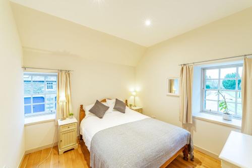 a bedroom with a bed and two windows at Wallace Apartment in Newton Stewart
